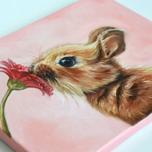 May include: A painting of a brown bunny rabbit sniffing a pink flower. The bunny has a fluffy brown coat and black eyes. The flower is a pink gerbera daisy with a green stem.