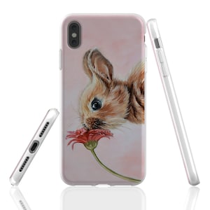 Puede incluir: Una funda de iPhone rosa con una pintura de un conejito marr&oacute;n oliendo una flor roja.