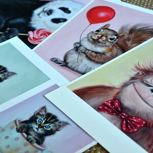 Puede incluir: Cinco postales ilustradas con animales adorables. Un panda sosteniendo una piruleta, una ardilla sosteniendo un globo rojo, un gatito en una taza de t&eacute;, otro gatito en una taza de t&eacute; y un orangut&aacute;n con una pajarita roja.