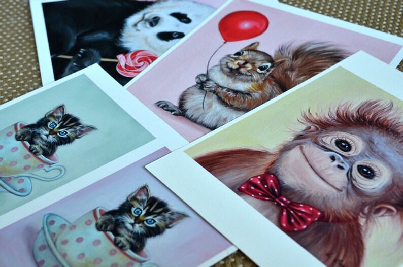 Puede incluir: Cinco postales ilustradas con animales adorables. Un panda sosteniendo una piruleta, una ardilla sosteniendo un globo rojo, un gatito en una taza de t&eacute;, otro gatito en una taza de t&eacute; y un orangut&aacute;n con una pajarita roja.