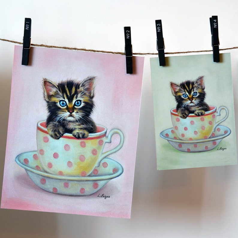Puede incluir: Una pintura de un gatito sentado en una taza de t&eacute; con lunares rosas. El gatito tiene ojos azules y mira al espectador. La taza de t&eacute; est&aacute; sobre un platillo con lunares rosas. El fondo es de color rosa claro.