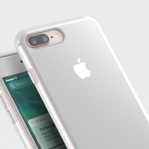 Puede incluir: Una funda para iPhone blanca con la parte posterior transparente y un logotipo de Apple blanco. La funda est&aacute; hecha de un material flexible y tiene un borde elevado alrededor del objetivo de la c&aacute;mara para protegerlo de los ara&ntilde;azos.