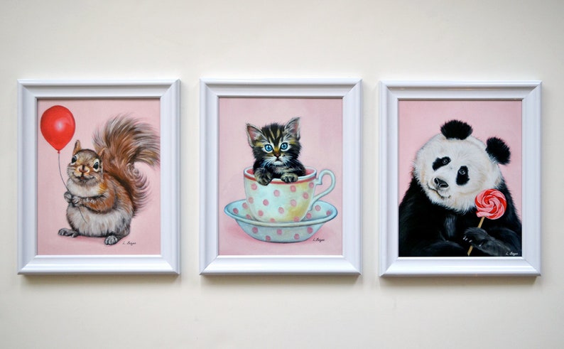 Puede incluir: Tres pinturas enmarcadas con fondos rosas. La primera pintura presenta una ardilla sosteniendo un globo rojo. La segunda pintura presenta un gatito sentado en una taza de t&eacute;. La tercera pintura presenta un panda sosteniendo una piruleta rosa.