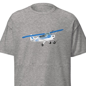May include: A gray t-shirt with a cartoon illustration of a small, white airplane with blue accents. The airplane has the registration number "N5953" on the side.