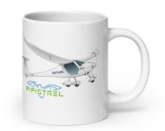 May include: A white ceramic mug featuring a graphic illustration of a white Pipistrel Sinus light sport aircraft. The design includes the text "SINUS" and "LIGHT SPORT" on the plane's fuselage, with the word "PIPISTREL" in green below it.