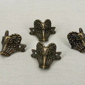 May include: Four antique gold corner protectors with a decorative ram's head design.