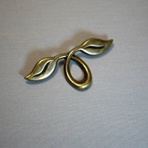 May include: A gold-toned metal leaf-shaped pendant with a loop at the top.