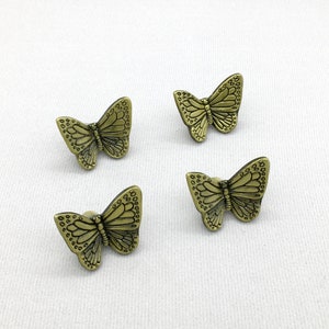 Puede incluir: Cuatro tiradores de cajón en forma de mariposa de color dorado. Cada tirador tiene un diseño detallado con un acabado texturizado.