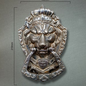 May include: A silver lion head door knocker with a crown and ornate details. The knocker measures 100mm wide and 210mm tall.
