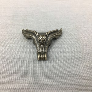 May include: A silver metal corner bracket with an owl design. The bracket has a decorative, ornate design with wings and a detailed owl face.