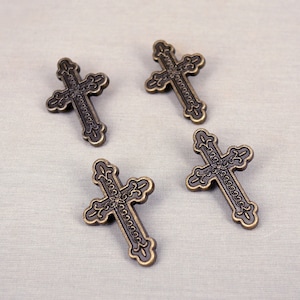 May include: Four ornate, antique gold-toned metal cross charms with intricate designs.