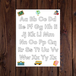 May include: A white sheet of paper with the alphabet written in black outlined letters. The letters are in uppercase and lowercase. There are illustrations of a schoolhouse, a globe, a school bus, and a stack of books with an apple on top.