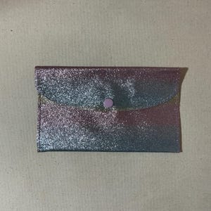 May include: A silver and pink glitter clutch with a pink button closure.