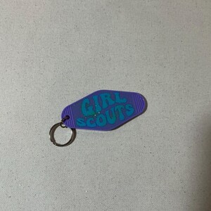 May include: Purple motel key chain with a blue glitter 'GIRL SCOUTS' design.