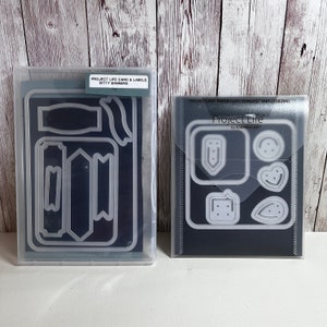 May include: Two clear plastic cases containing metal dies for paper crafting. One case has banner and label shapes, the other has paper clip and decorative shapes. The text on the cases reads "Project Life" and "Bitty Banners".