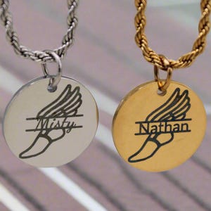May include: Two gold and silver necklaces with a winged foot pendant. The pendants are engraved with the names "Misty" and "Nathan".
