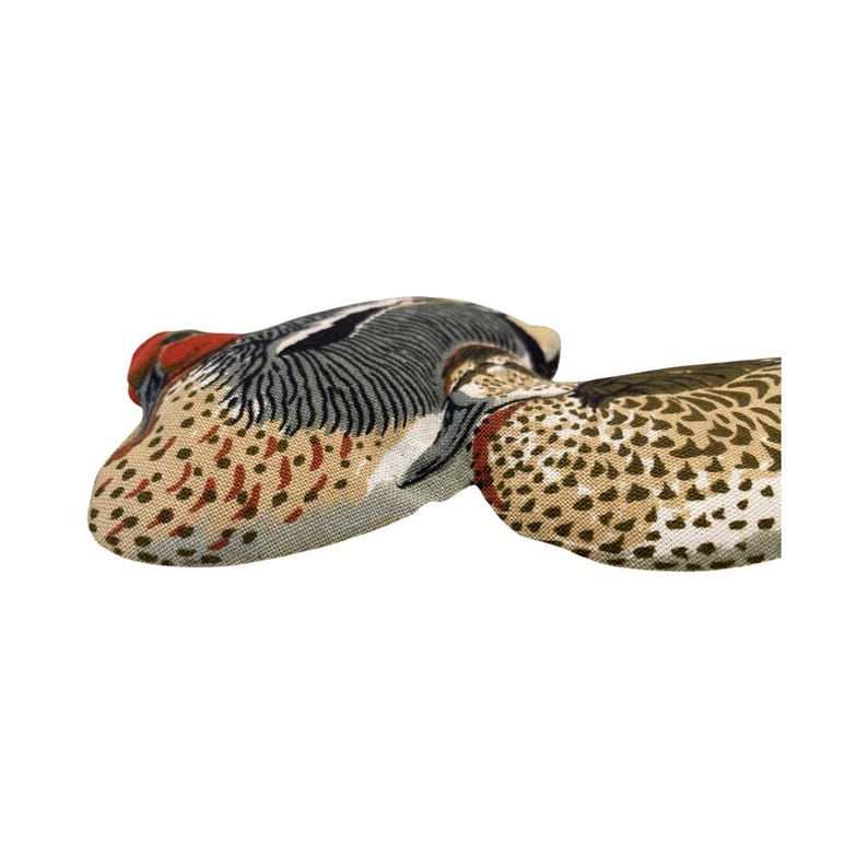 May include: Two fabric duck-shaped pillows with a brown, green, and red patterned design.