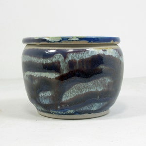 Op de afbeelding: Een blauwe en witte keramische plantenpot met een geglazuurde afwerking. De pot heeft een ronde vorm en een brede opening.