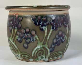 Mantequera francesa de color verde bosque con flores moradas y rojas.