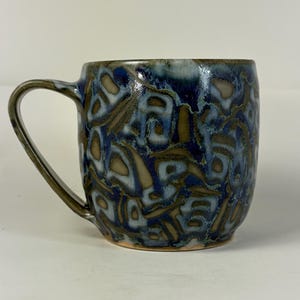 Puede incluir: Un juego de tres tazas de cerámica con un acabado mate moteado. Las tazas son en tonos crema, gris claro y gris oscuro. Cada taza tiene un diseño simple y minimalista, perfecto para café o té.