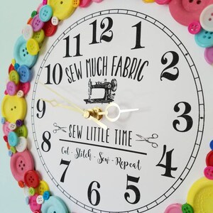 May include: A white clock with black numbers and hands, surrounded by colorful buttons. The clock face reads "10 Sew Much Fabric" and "Sew Little Time Cut - Stitch - Sew - Repeat".