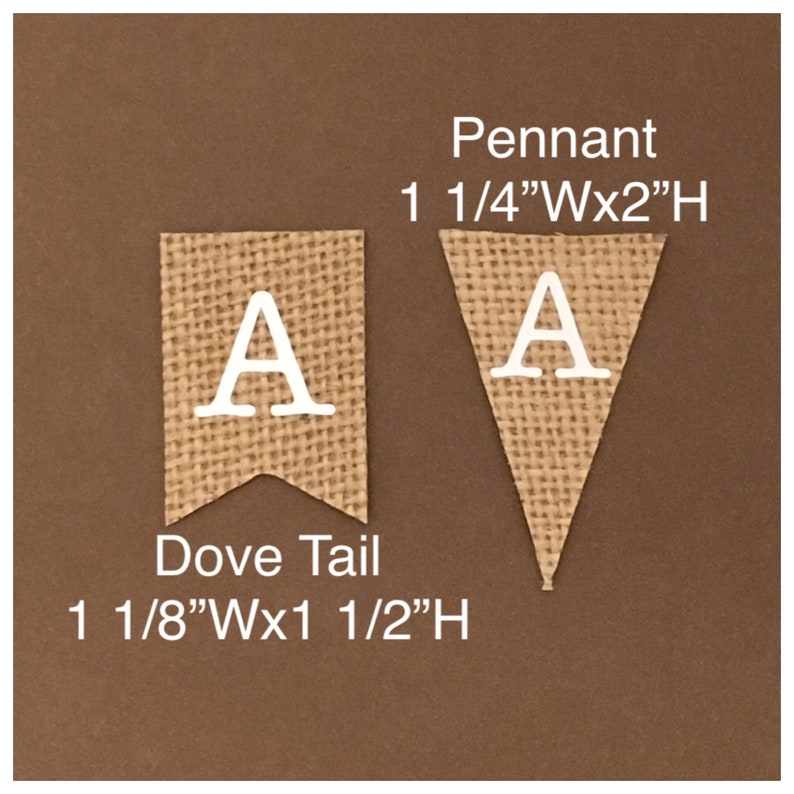 Puede incluir: Dos banderines de arpillera, uno de cola de milano y otro triangular, cada uno con la letra blanca "A". El bander&iacute;n de cola de milano mide 2,9 cm de ancho x 3,8 cm de alto. El bander&iacute;n triangular mide 3,2 cm de ancho x 5,1 cm de alto.