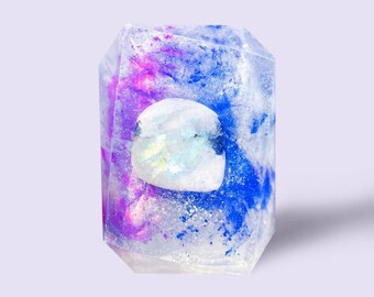 May include: A clear, iridescent soap bar with a blue and purple swirl design. The soap has a white, iridescent center.