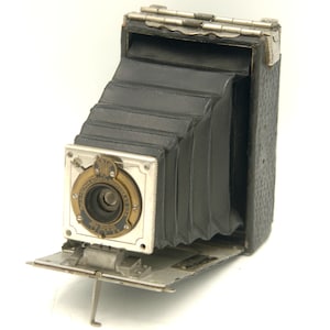 May include: A vintage black and silver folding camera with a bellows and a lens marked "The Eastman Kodak Co. Rochester, N.Y. U.S.A."