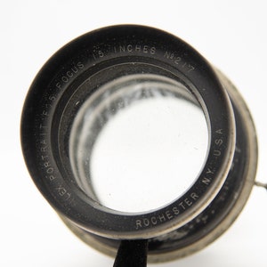 May include: A black and silver lens with the text "Lex Portrait F.S. Focus 15 Inches No. 217 Rochester N.Y. USA" engraved around the edge.