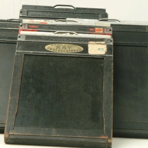 May include: A black wooden camera back with a brass handle and a label that reads "Gene & Ann Kay's Photographers 43".