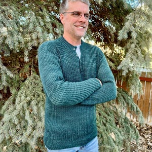 May include: A dark green sweater with a button-up collar and a ribbed texture. The sweater is made of a soft, comfortable material.