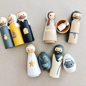 May include: A set of wooden figurines depicting the Nativity scene. The figures include Mary, Joseph, baby Jesus, a donkey, a sheep, and three wise men. The figures are painted in various colors, including brown, white, yellow, and gray.