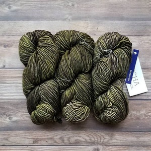 May include: Two skeins of green yarn with a dark green and light green color gradient. The yarn is labeled "Acha" and "Das Chircas".