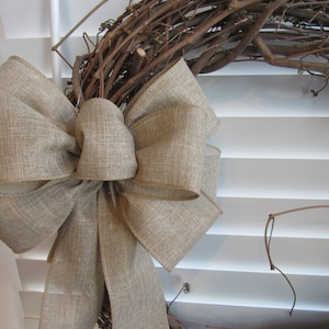 May include: A large, brown burlap bow tied in a simple knot. The bow is made of a coarse, woven fabric and has a rustic, natural look.