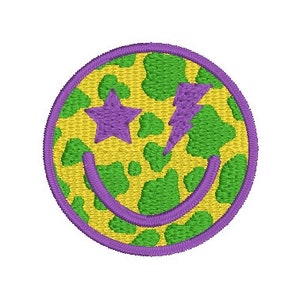 May include: A yellow and green smiley face with a purple star and lightning bolt for eyes. The smiley face has a cow print pattern.