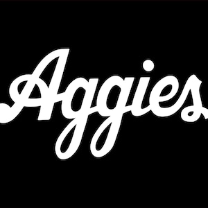 May include: White script text that reads "Aggies" on a black background. The word is in a cursive font with a decorative flourish on the letter "A" and the letter "s". The background is solid black.