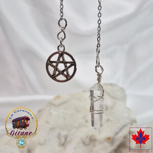 May include: A silver-toned metal chain necklace featuring a circular pentagram charm and a clear, faceted crystal point pendant wrapped in silver wire. The design includes a delicate link chain that suspends both the charm and the crystal.