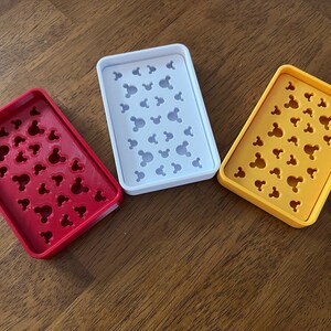 May include: Three soap dishes with Mickey Mouse head designs. The dishes are red, white, and yellow.