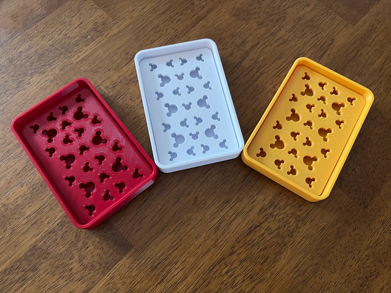 May include: Three soap dishes with Mickey Mouse head designs. The dishes are red, white, and yellow.