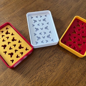 May include: Three soap dishes with a Mickey Mouse head design. The dishes are yellow, white, and red with a yellow border.