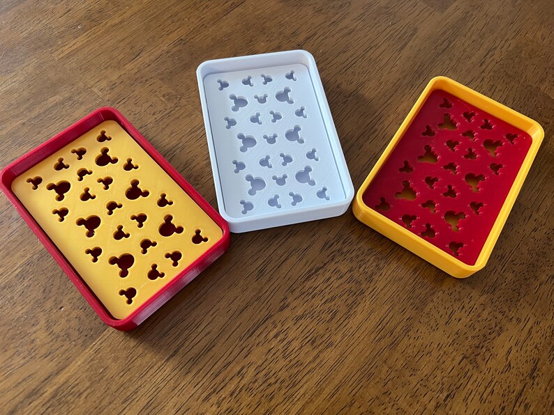 May include: Three soap dishes with a Mickey Mouse head design. The dishes are yellow, white, and red with a yellow border.
