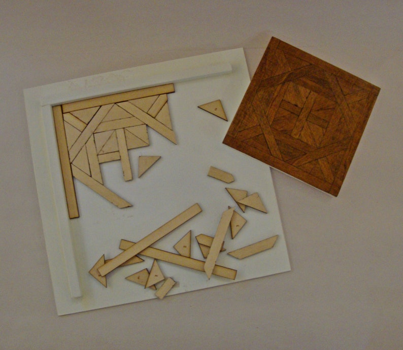 May include: A wooden puzzle with a partially assembled section and scattered pieces. The puzzle features a geometric design with various shapes and angles. A separate, completed square wooden piece with a patterned design is also present.