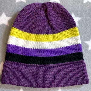 May include: Purple, white, yellow, and black striped knitted beanie hat.