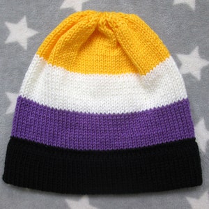 May include: A knitted beanie hat with yellow, white, purple, and black stripes. The hat is made of soft yarn and has a comfortable fit.