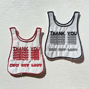 May include: Two white fabric patches in a shopping bag shape. One has red trim and text that says "THANK YOU" repeated and "NOW GET LOST". The other has black trim and text that says "THANK YOU" repeated and "NOW GET LOST".
