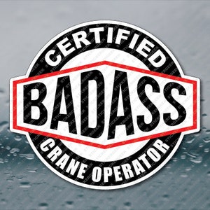 May include: A black and white sticker with red accents. The sticker reads "Certified Badass Crane Operator".