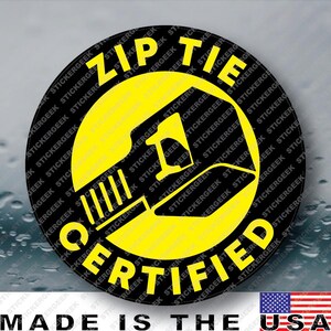 May include: A circular sticker with a black background and a yellow border. The center features a yellow graphic of a zip tie. The text ZIP TIE is printed in yellow at the top, and CERTIFIED is printed in yellow at the bottom of the circle.
