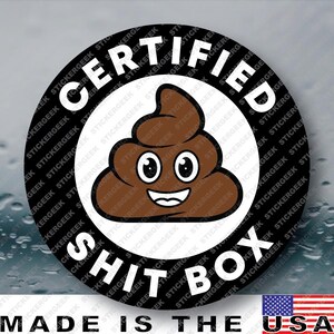 May include: A circular sticker with a black border and a white center featuring a brown cartoon poop emoji with a smiling face. The text CERTIFIED SHIT BOX is printed in white capital letters around the circular black border of the sticker.