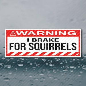 May include: A red and white warning sign with black text that reads "WARNING I BRAKE FOR SQUIRRELS". The sign has a black exclamation point and diagonal red and white stripes.