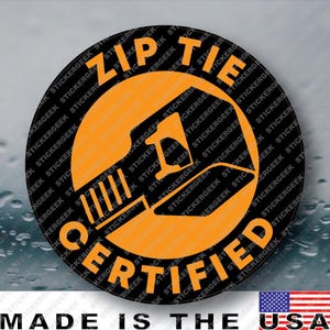 May include: A circular sticker with a black background and an orange graphic of a zip tie tool in the center. The text ZIP TIE is printed in orange along the top edge, and the word CERTIFIED is printed in orange along the bottom edge.